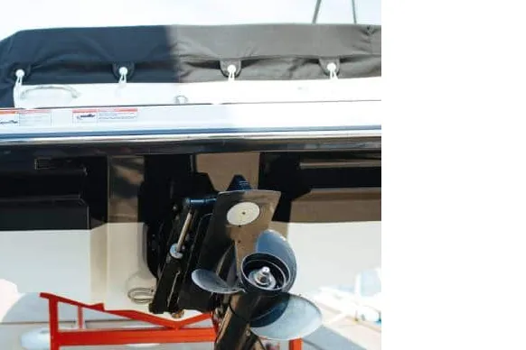 Marine mechanic servicing an outboard drive and propeller at the dock
